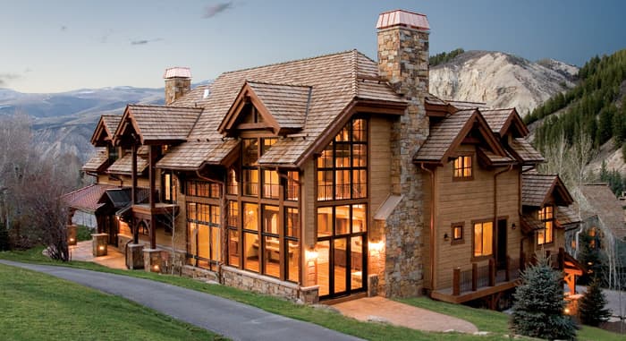 A timber and stone house with lit windows at dusk